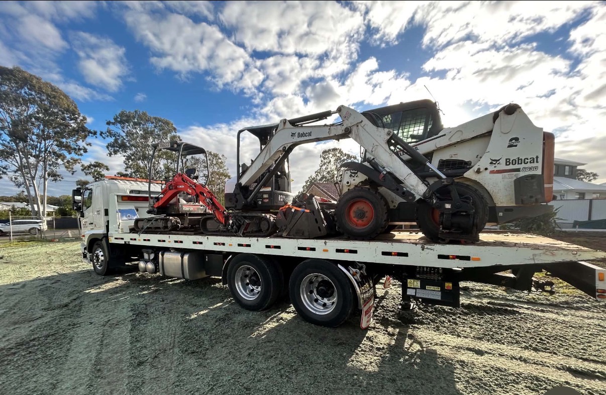 Wazza's bobcat and excavator fleet loaded on a tipper truck